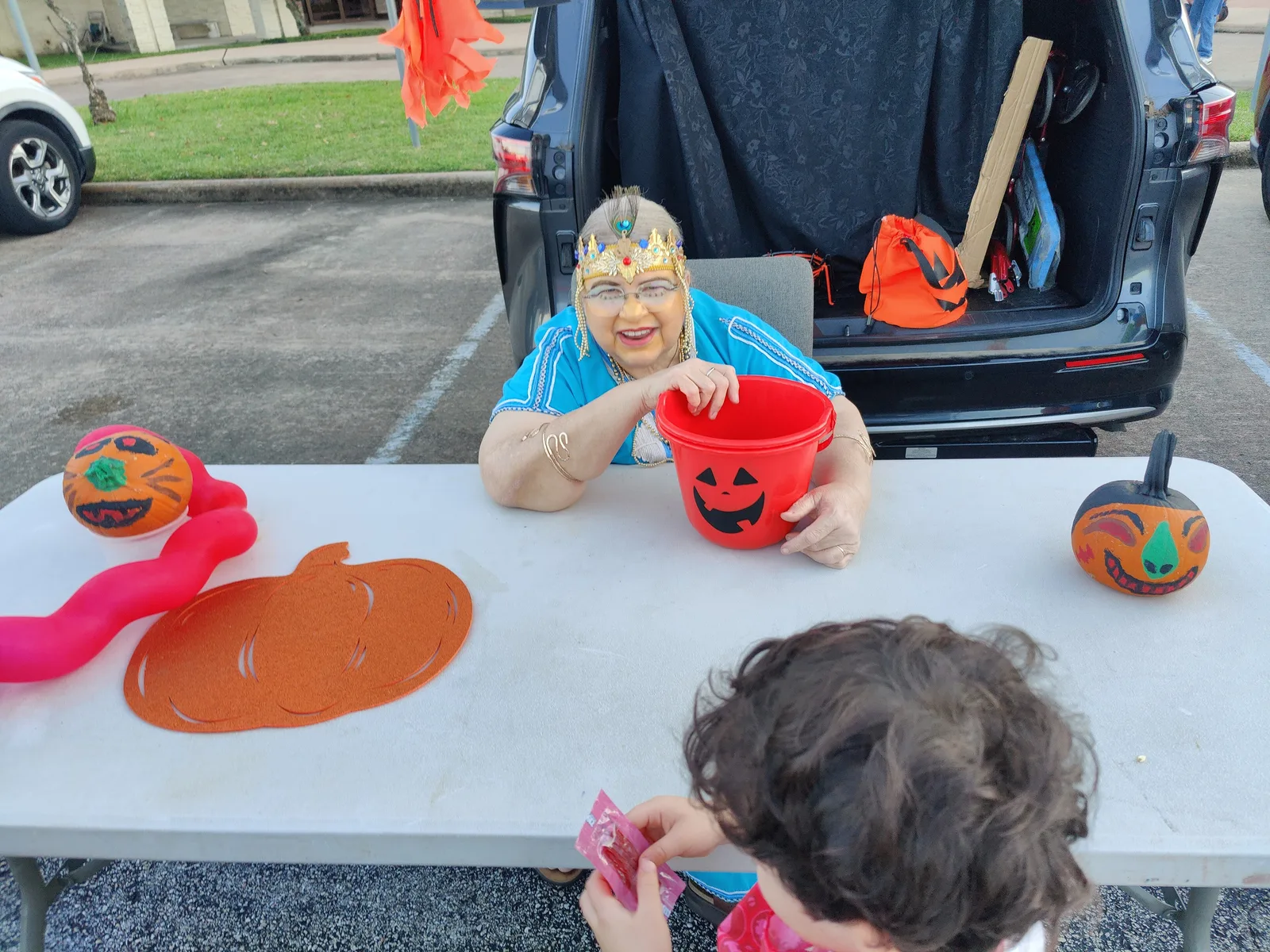 A volunteer hands out candy beside a decorated car trunk at a church trunk-or-treat in Houston, Texas.