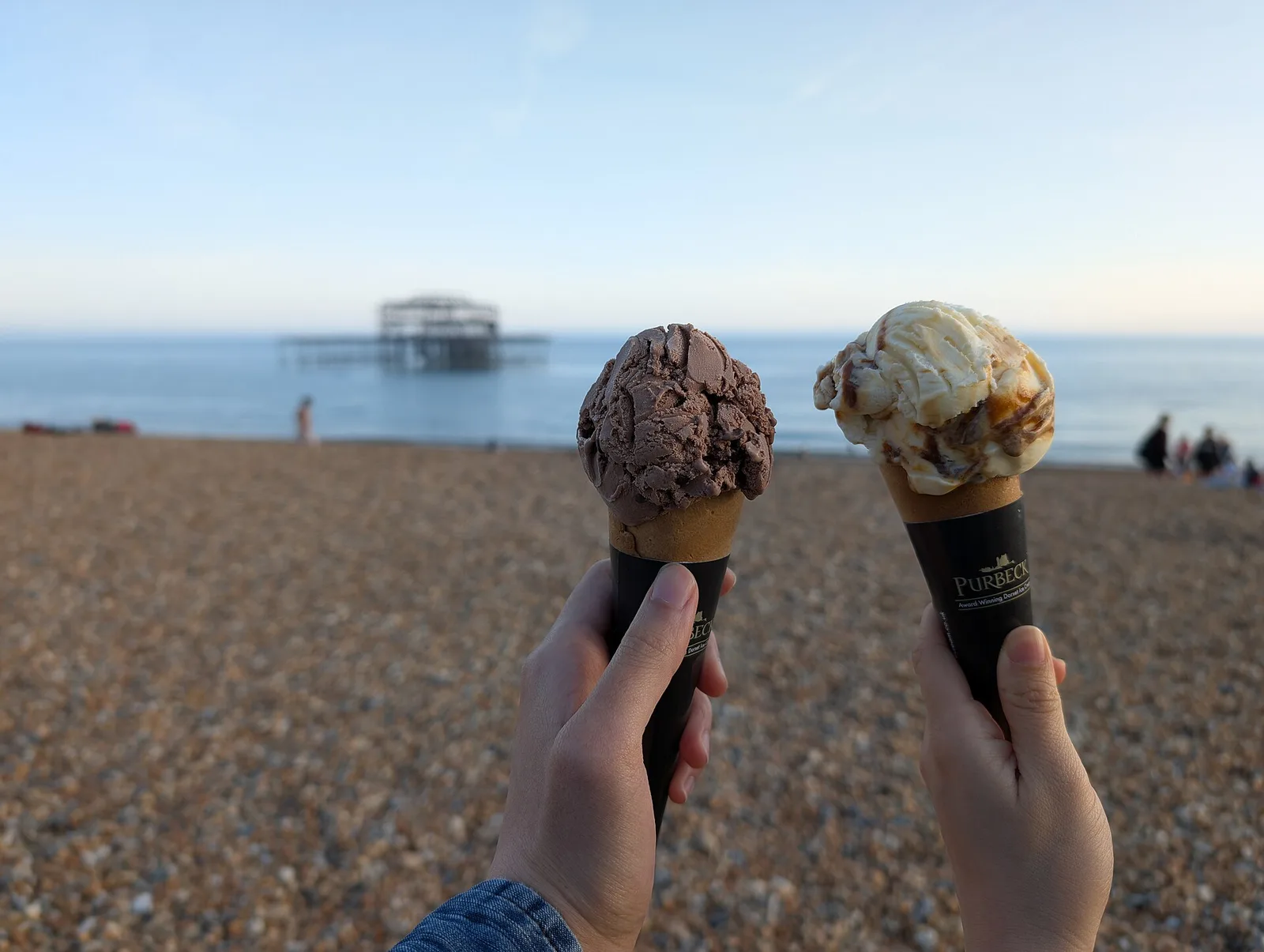 Two ice cream cones held up outdoors. The photo was not taken in Apex.