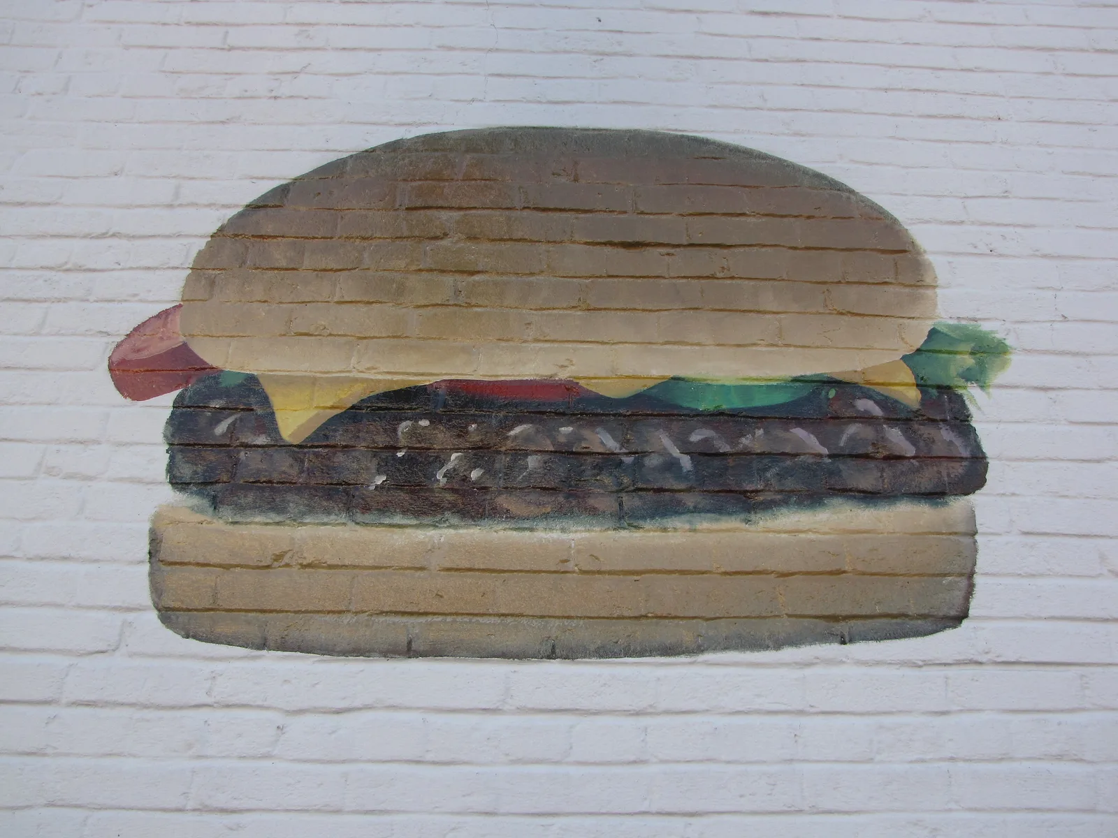 A cheeseburger with lettuce, tomato and onion on a plate. The photo was not taken in Apex.